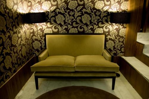 a green couch in a room with wallpaper at Hotel Opera in Madrid