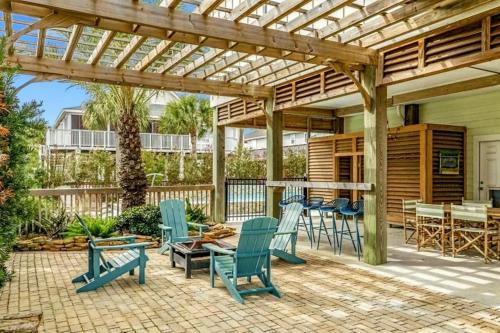Un patio con sillas azules y una pérgola de madera. en Beachside Dream, Heated Poolhot Tub, 2 King Beds, en Galveston