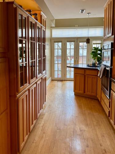 a large kitchen with wooden cabinets and a wooden floor at 3 br Spacious Home in Ideal Location w Free Parking Back Yard Pets Welcome in Chicago