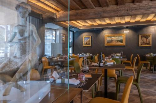 a restaurant with tables and chairs and a sculpture at Locanda degli Artisti Art Hotel in Canazei