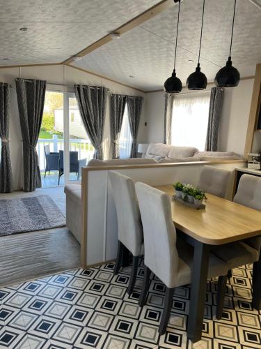 a dining room and living room with a table and chairs at The Luxe Lodge, Skipsea Sands Bridlington in Ulrome