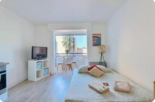 un salon blanc avec un lit et une télévision dans l'établissement Appartement Instant Cozy Proche Mer avec Parking, à La Ciotat