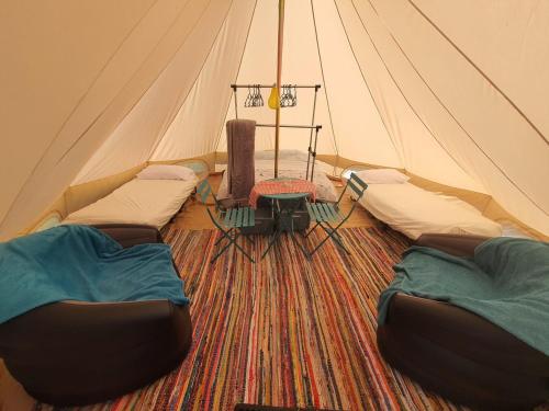 a tent with three beds and a table in it at Koppány Pines - Bell Tent B & B Rooms in Koppányszántó