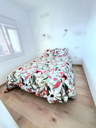 Un dormitorio con una cama con un edredón floral. en La casa de la playa, en Playa Quemada