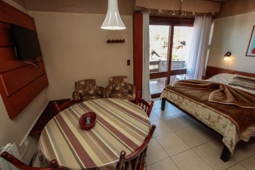 a bedroom with a bed and a table and chairs at pousada do serrano in Gramado