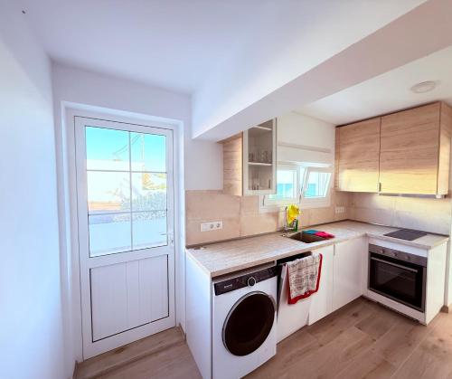 cocina con lavadora, fregadero y ventana en La casa de la playa, en Playa Quemada