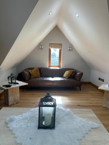 a living room with a brown couch in a attic at Turnhams Gill located near high street in Henfield