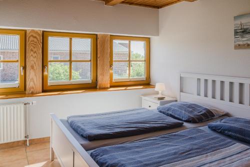une chambre avec deux lits et deux fenêtres dans l'établissement Ferienwohnung Fachwerkhaus - Süden unten - Bauernhof Hopp Vadersdorf, à Fehmarn
