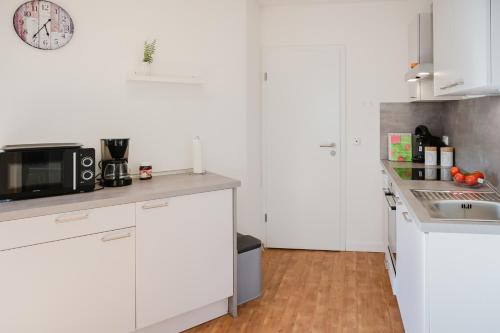 une cuisine avec des armoires blanches et un micro-ondes dans l'établissement Landhaus Ferienwohnung 1 - Bauernhof Hopp Vadersdorf, à Fehmarn