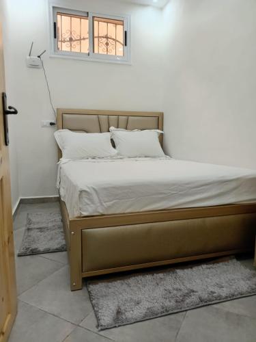 un letto con lenzuola e cuscini bianchi in una camera da letto di Taghazout Flat a Taghazout