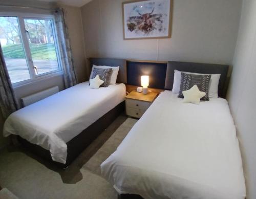 two beds in a small room with a window at Sea Breeze, Vintage 90, Luxury 2 bed Lodge, Skegness, 2 friendly - East Coast Holidays in Winthorpe
