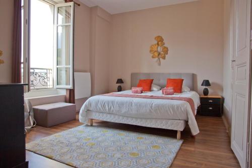 une chambre avec un lit avec des oreillers orange et une fenêtre dans l'établissement Charmant T3 ,100m2, centre ville, classé 3 étoiles, à Aix-les-Bains