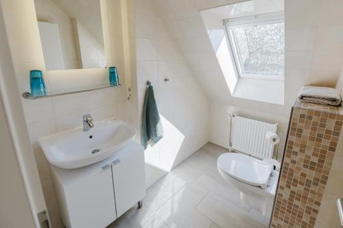 ein weißes Badezimmer mit Waschbecken und Toilette in der Unterkunft Landhaus Ferienwohnung 2, Bauernhof Hopp Vadersdorf in Fehmarn
