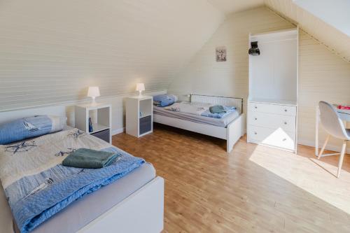 ein Schlafzimmer mit einem Bett und einer Kommode sowie einem Bett und einem Stuhl in der Unterkunft Landhaus Ferienwohnung 2, Bauernhof Hopp Vadersdorf in Fehmarn