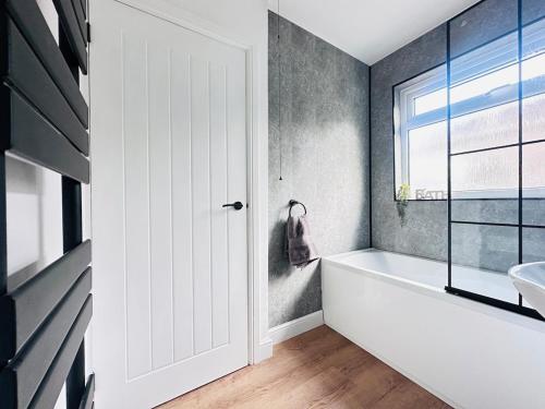 ein Badezimmer mit einer weißen Badewanne und einem Waschbecken in der Unterkunft Comfy 4 Bed Home - Port Talbot - Perfect for Contractors & Families in Port Talbot