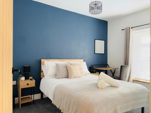 ein Schlafzimmer mit blauen Wänden und einem großen Bett in der Unterkunft Comfy 4 Bed Home - Port Talbot - Perfect for Contractors & Families in Port Talbot