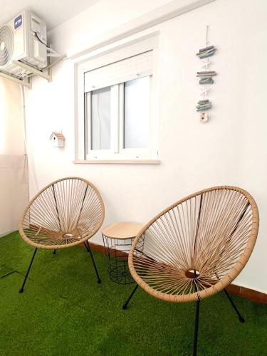 Dos sillas y una mesa en una habitación con alfombra verde. en Apartamento centro Punta Umbría, en Punta Umbría