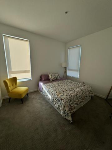a bedroom with a bed and a yellow chair at Modern Unit Near Glendale Galleria and Walk to Shopping & Dining! in Glendale