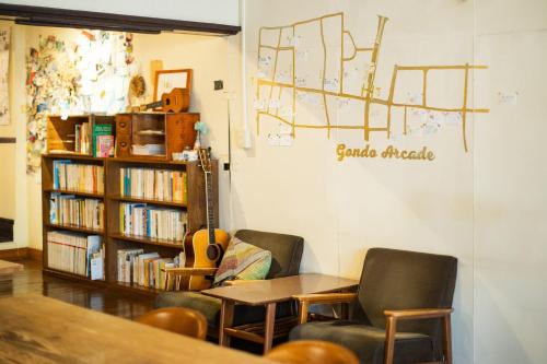 a room with two chairs and a book shelf with books at 1166 Backpackers in Nagano