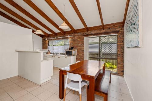 a kitchen with a wooden table and white appliances at Coastal Paws Pet friendly, family beach house in Pottsville in Pottsville