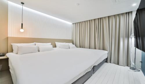 a bedroom with a large white bed and a television at 호텔그랑파리 in Gwangju