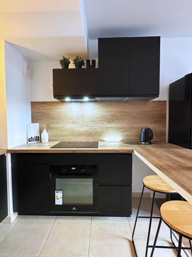 une cuisine avec des placards noirs et un comptoir avec des tabourets dans l'établissement Dandy home F2 proche Paris et Aéroport Orly, à Thiais