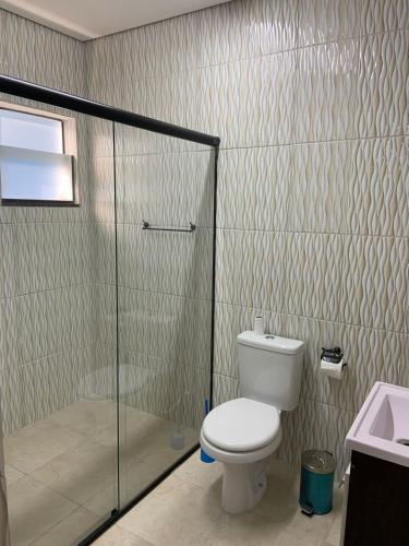a bathroom with a toilet and a glass shower at Pousada Rancho Bananas Felizes in Miracatu
