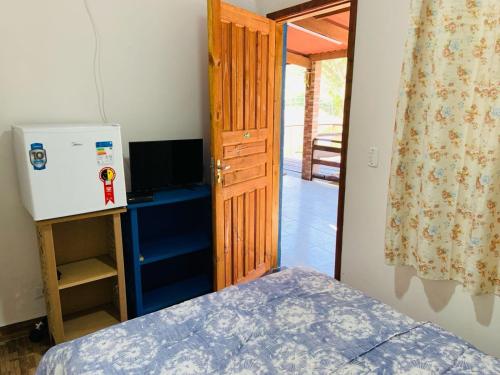 a room with a bed and a refrigerator and a door at Pousada Rancho Bananas Felizes in Miracatu