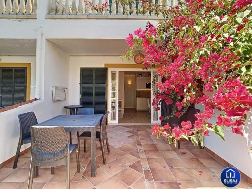 una mesa y sillas en un patio con flores rosas en Can Alfredo, Apartamento Cala en Bosch con piscina, terraza y jardín privado, en Cala'n Bosch