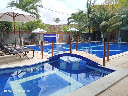 a swimming pool with a blue tile floor and an umbrella at WS Beach Pousada in Porto De Galinhas