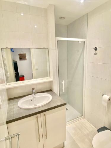 une salle de bain blanche avec un lavabo et une douche dans l'établissement ÎLE D OLÉRON Charmante Maison Oléronaise & Piscine chauffée, à Saint-Georges-dʼOléron