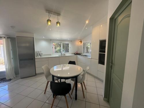 une cuisine avec une table et des chaises dans une pièce dans l'établissement Villa Plage à 130 m SPA Piscine partagés, à Soulac-sur-Mer