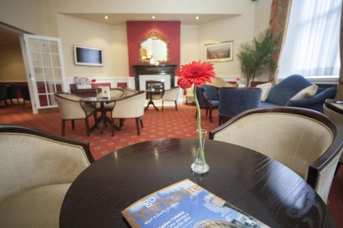 a room with a table with a vase with a flower on it at The White Swan Hotel in Halifax