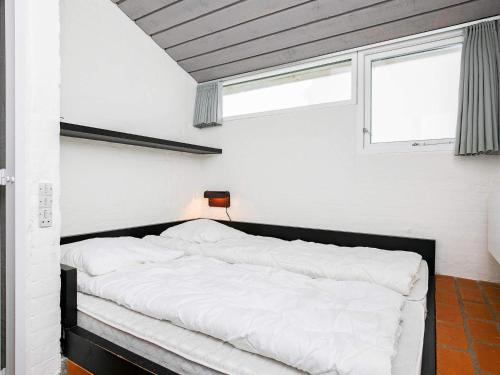 a bedroom with a bed with white sheets and a window at 6 person holiday home in Brovst in Brovst