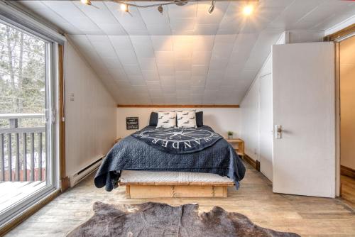 a bedroom with a bed and a large window at Le Pionnier Waterfront Lac-Supérieur Tremblant in Lac-Superieur