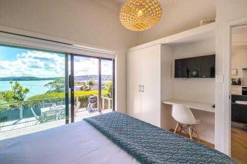 ein Schlafzimmer mit Bett und Blick auf das Meer in der Unterkunft Black Cottage - Stay Waiheke in Waiheke Island