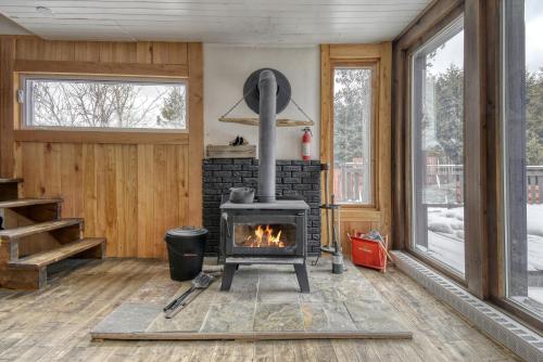 a fireplace in a living room with a stove at Le Pionnier Waterfront Lac-Supérieur Tremblant in Lac-Superieur