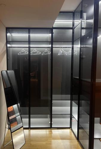 a black glass cabinet with a mirror and a ladder at 180° View Apartment in Diamond Building Skopje in Skopje