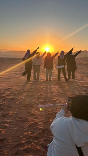 a group of people standing in the desert at sunset at Maha Wadi Rum in Wadi Rum
