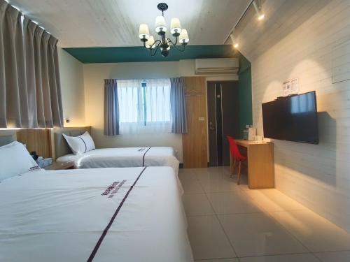 a hotel room with two beds and a flat screen tv at 筑月馆民宿 in Jinning