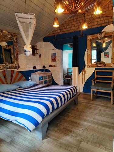 a bedroom with a bed with blue and white stripes at Hôtel Parthenay in Manakara