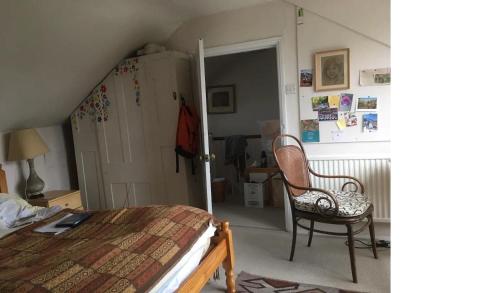 a bedroom with a bed and a chair in it at Private attic in Georgian townhouse with free parking in Leamington Spa