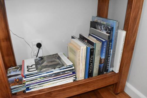 a pile of books sitting on a shelf at Te Hoiere Guesthouse in Havelock
