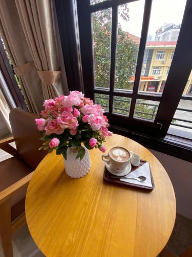 a table with a vase of pink flowers on it at Lavande Hue Homestay in Hue