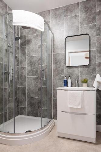 a bathroom with a shower with a sink and a mirror at Modern 2 Bedroom, 2 Bathroom Apartment in Central Belfast, Sleeps 6 with Parking Included in Belfast
