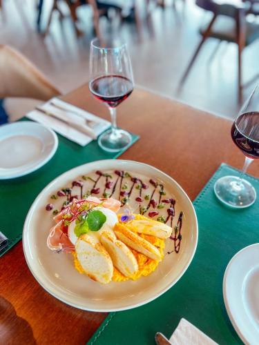 a plate of food on a table with wine glasses at Caminho das Nuvens - Cabanas de Montanha in Bom Retiro