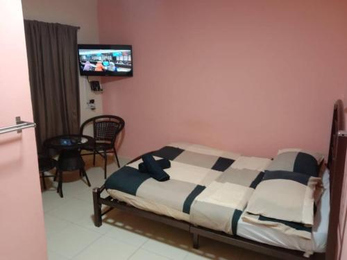 a bedroom with a bed and a tv on the wall at Ali's Guest House in Batu Ferringhi