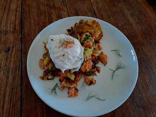 a white plate of food on a wooden table at Te Hoiere Guesthouse in Havelock