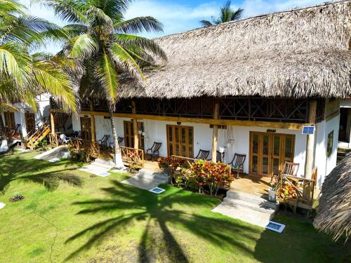 a building with a straw roof and a palm tree at Casa Origen Boutique en San Bernardo del Viento in San Bernardo del Viento