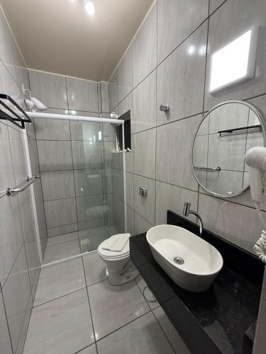 a bathroom with a toilet and a sink and a shower at Oasis Chartouni Hotel in Blumenau